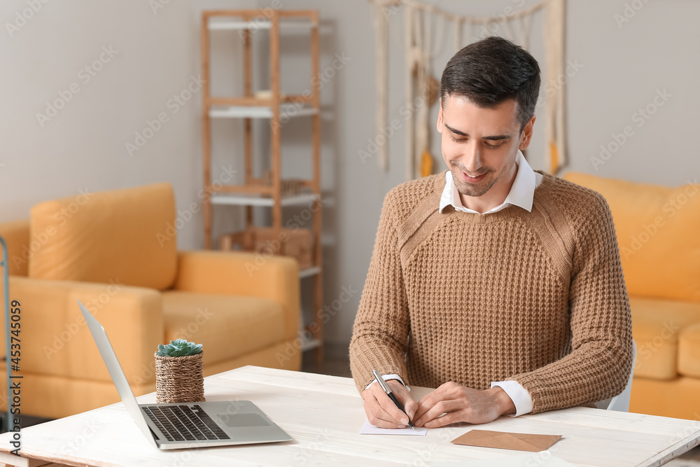 Young man writing letter at home