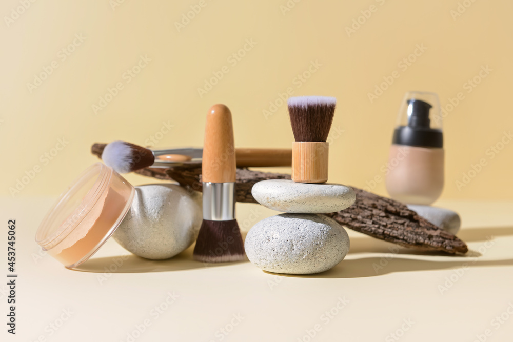 Makeup brushes with tree bark and spa stones on color background