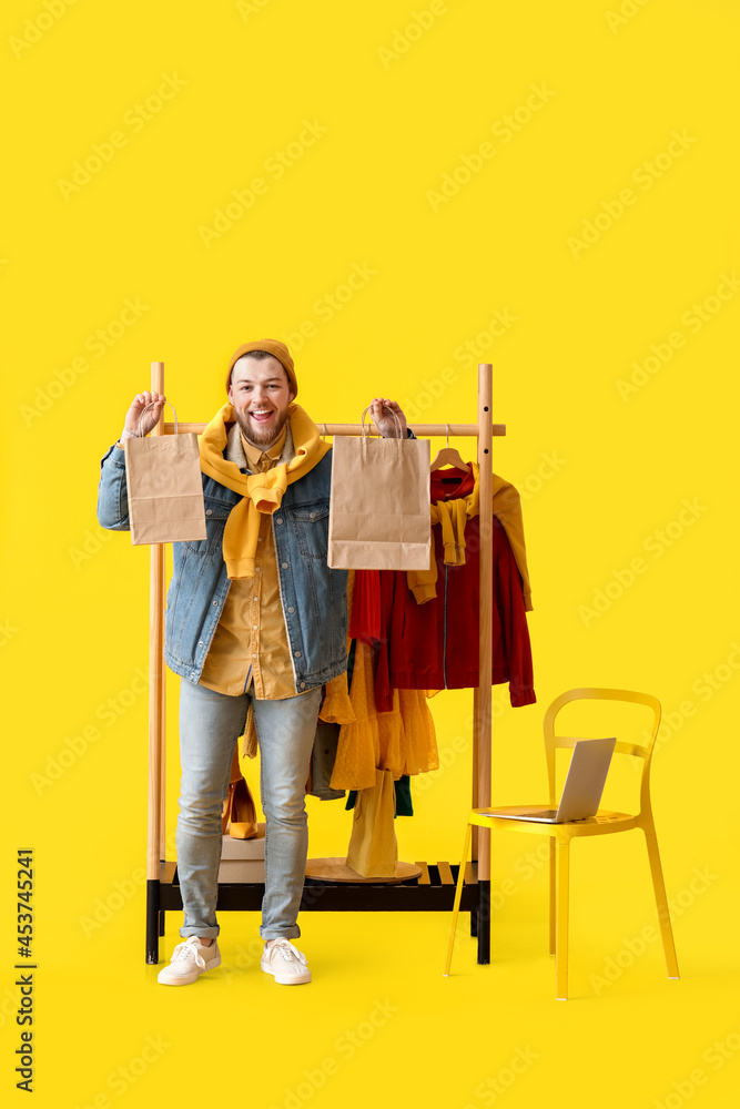 Male stylist with shopping bags on color background