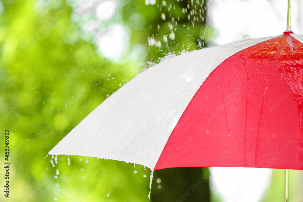 Open umbrella under falling rain drops outdoors