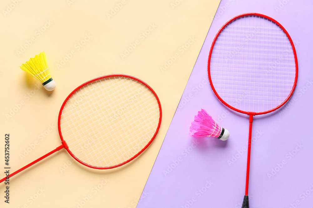 Badminton rackets and shuttlecocks on color background