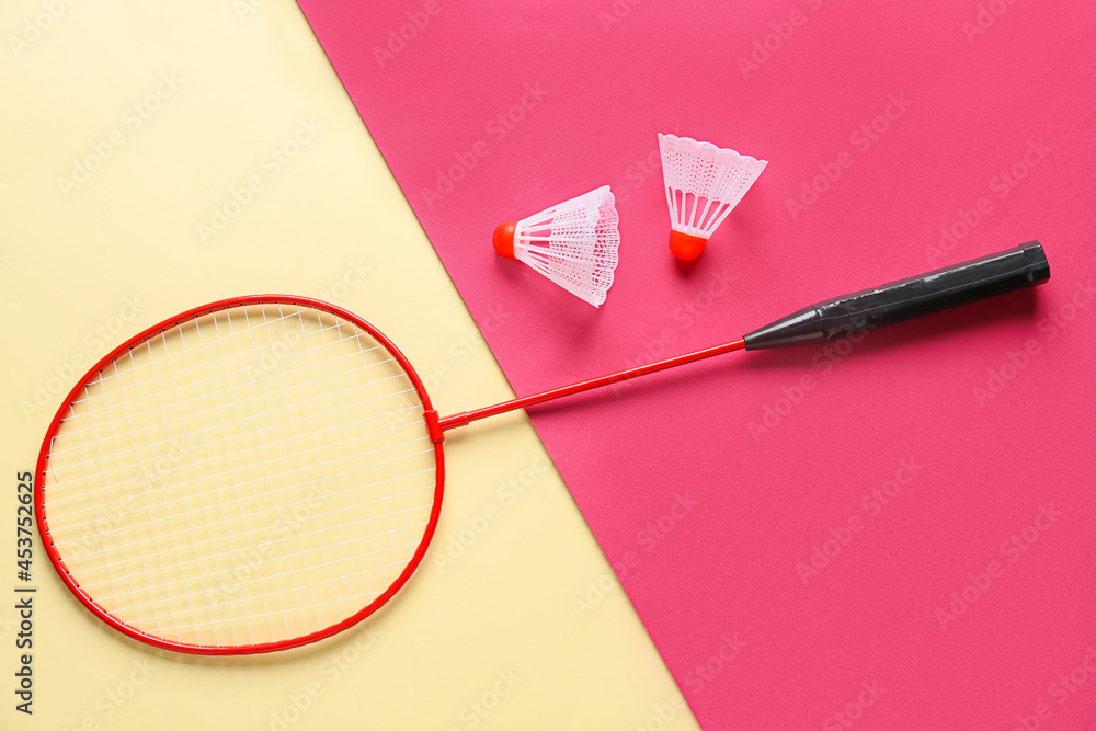 Badminton racket and shuttlecocks on color background