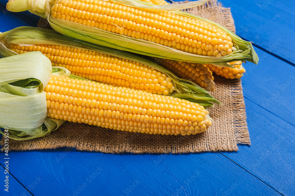 Fresh corn cobs on color wooden background, closeup