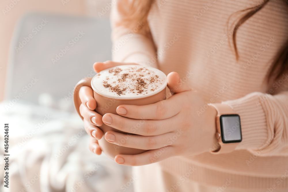 Young woman with cup of coffee at home, closeup