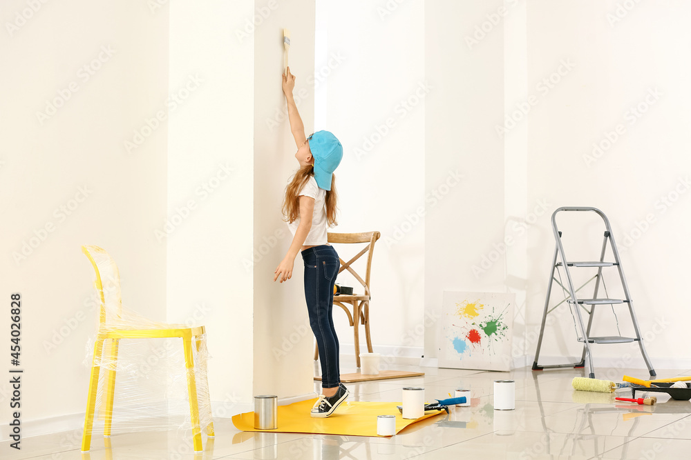 Little girl painting wall in room