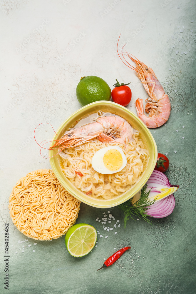 Bowl of tasty Thai soup with shrimps and ingredients on color background