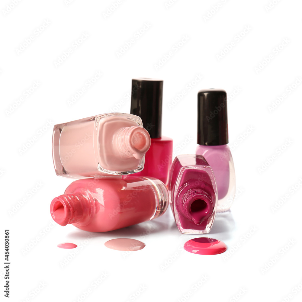 Overturned bottles of nail polishes on white background