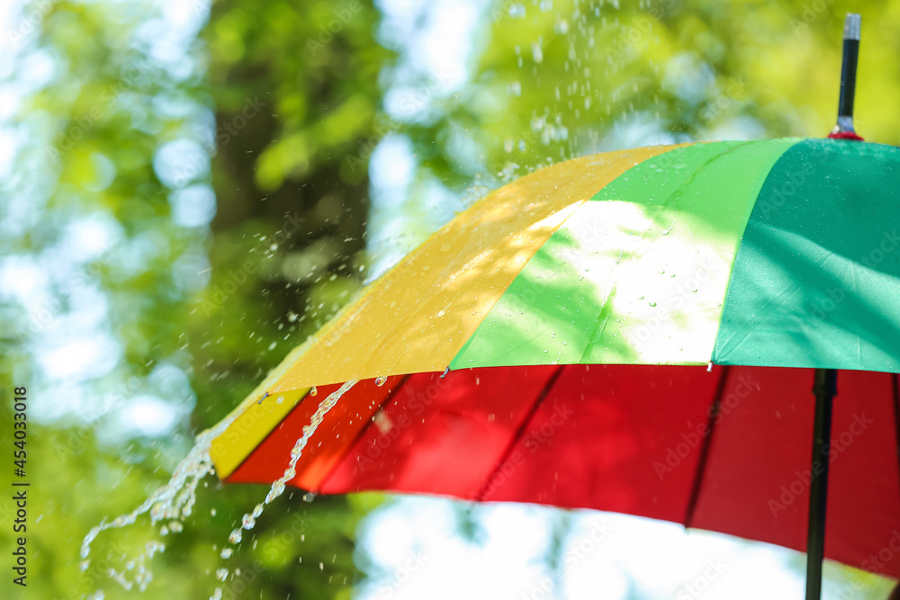 Open umbrella under falling rain drops outdoors