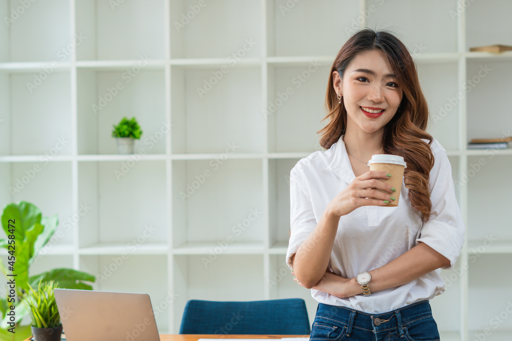 亚洲女商人在办公室里拿着一杯咖啡