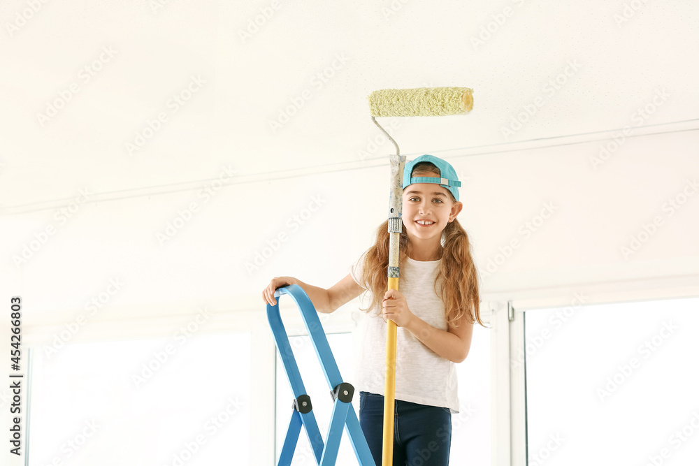 Little girl with paint roller on ladder in room