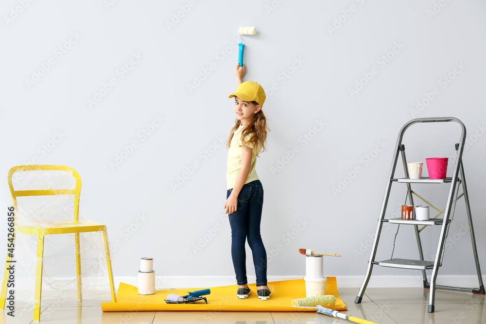 Little girl painting wall in room