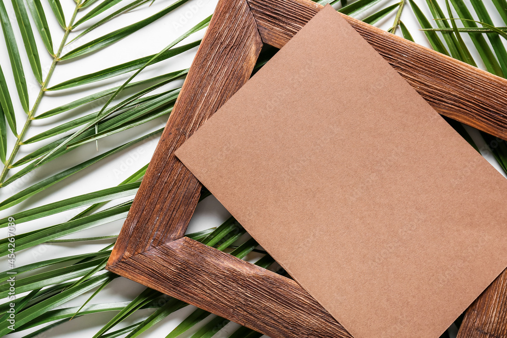 Composition with blank card, empty picture frame and palm leaves on white background, closeup