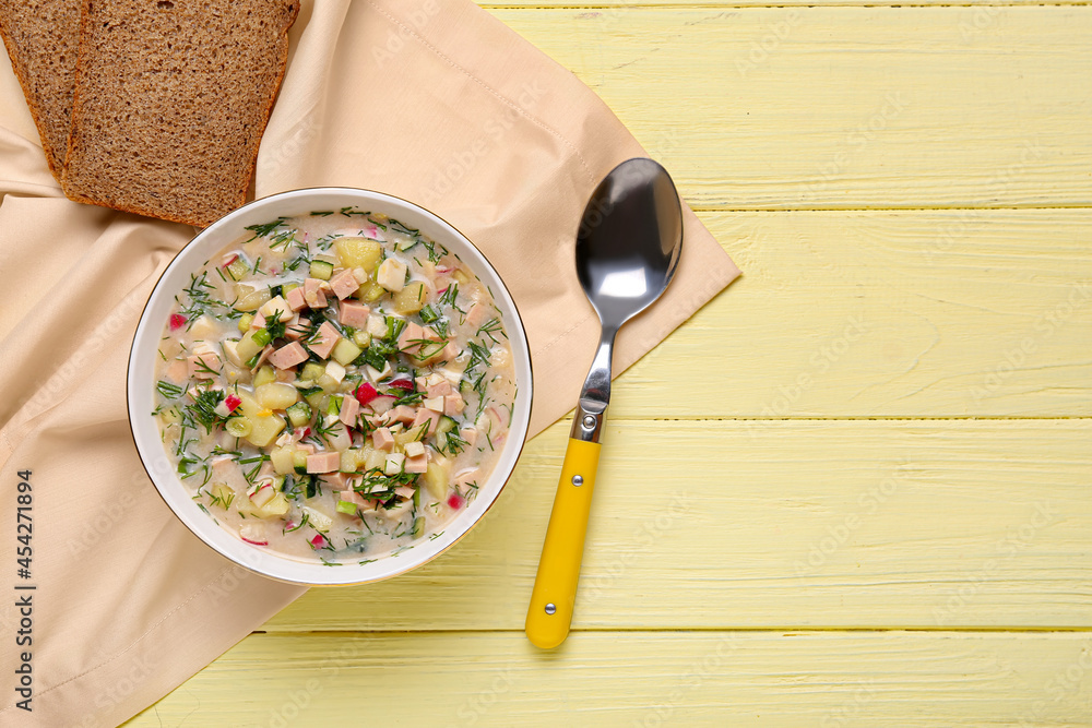 Bowl with tasty okroshka and bread on color wooden background