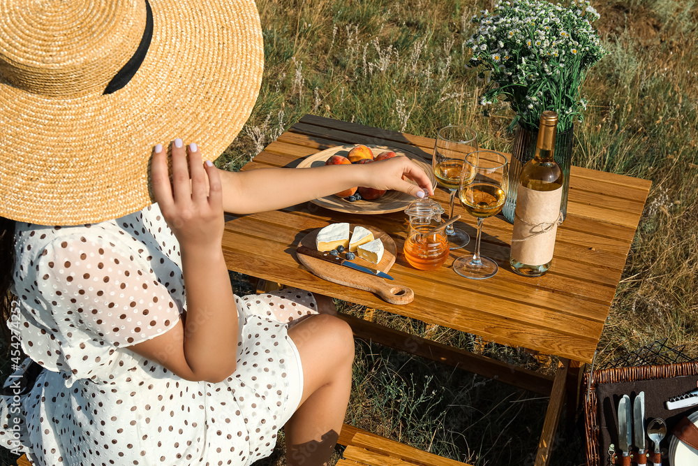 Young woman waiting for her boyfriend on romantic picnic outdoors