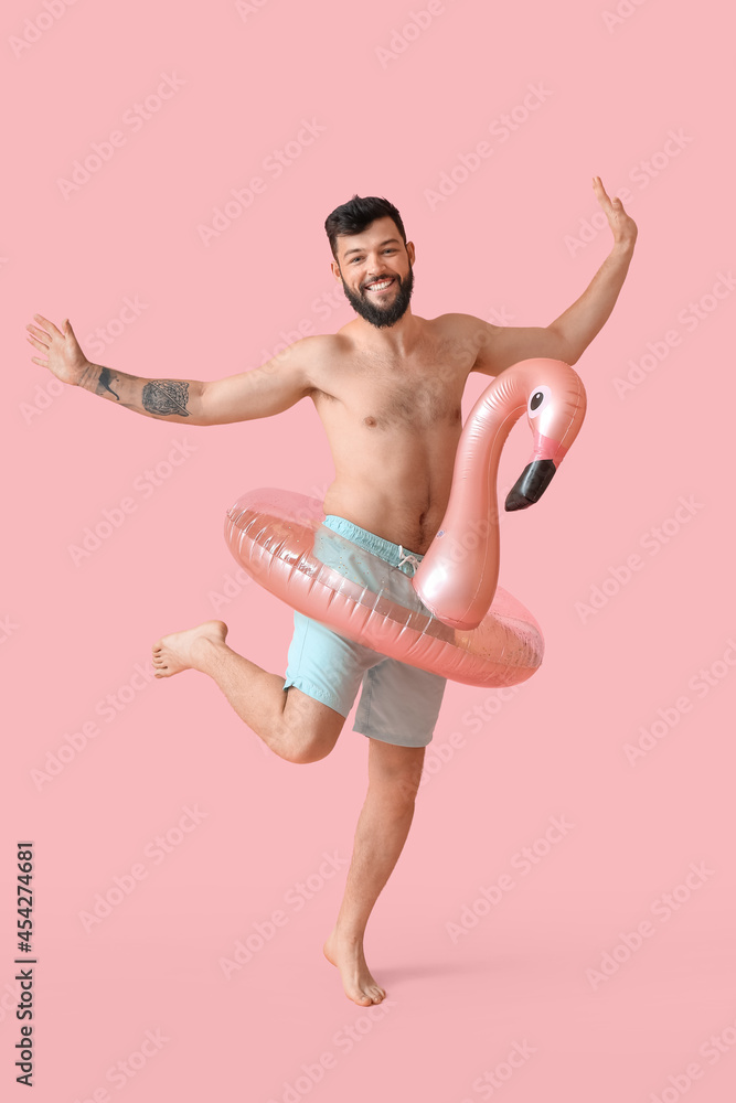 Funny young man with inflatable ring on color background