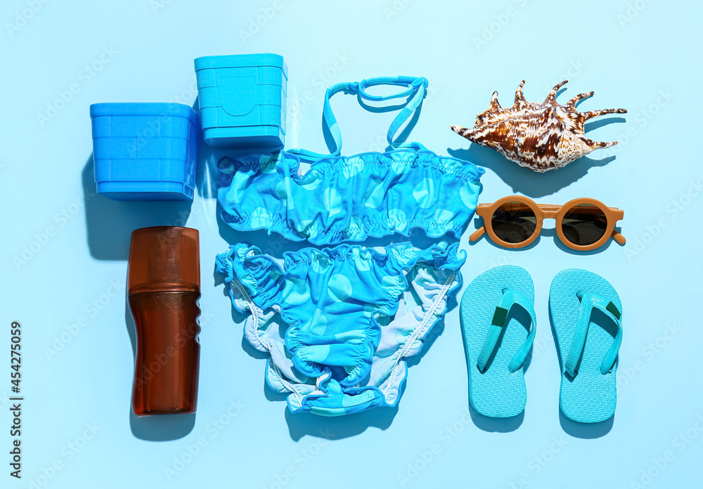 Set of beach accessories for children and bottle of sunscreen on color background