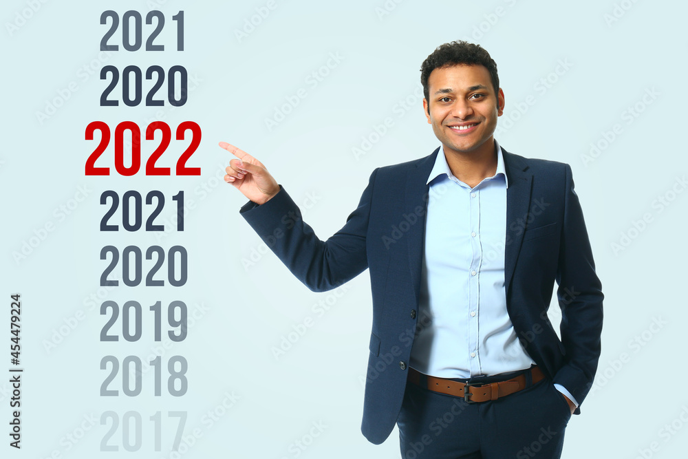 年轻的商人指着2022年的数字，以及其他背景上的数字