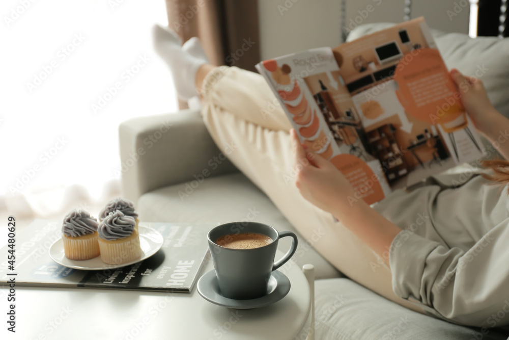 Cup of coffee and cupcakes on table in room