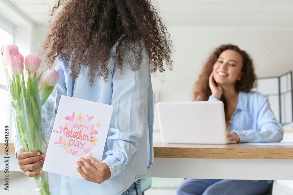 African-American little girl with greeting card and flowers for her mother at home