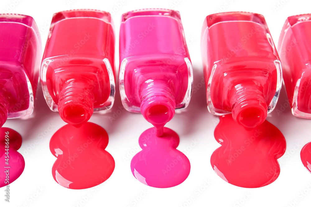 Overturned bottles of nail polishes and blots on white background