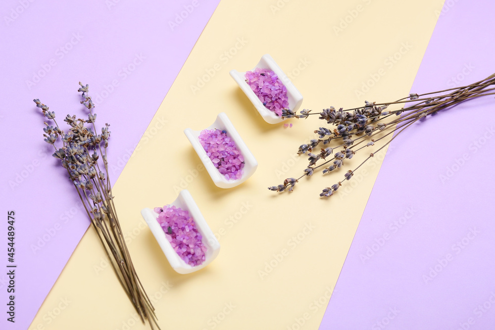 Bowls with sea salt and lavender flowers on color background