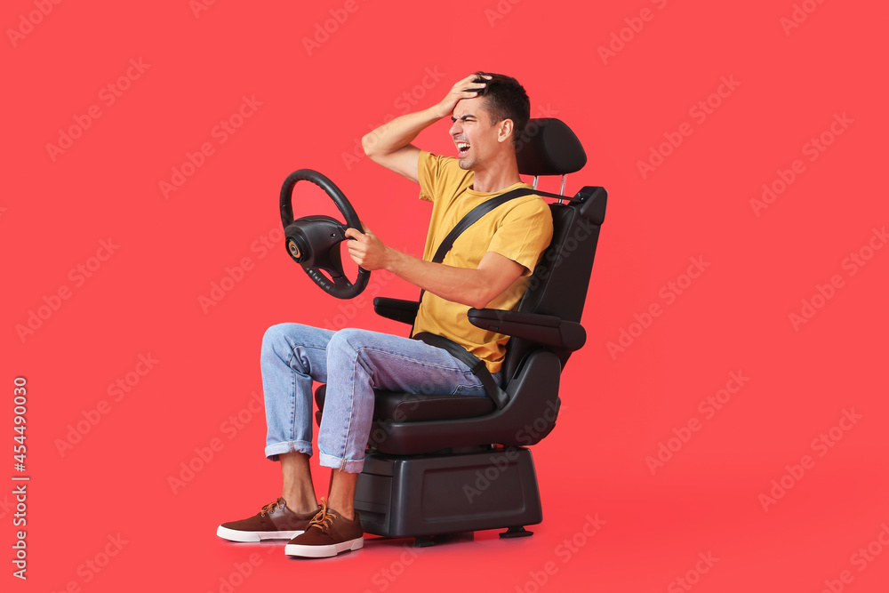 Angry man in car seat and with steering wheel on color background