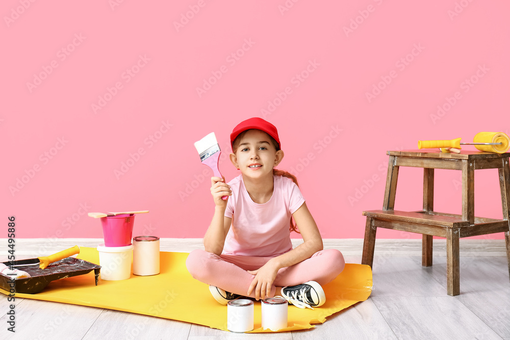 Little painter with brush near color wall