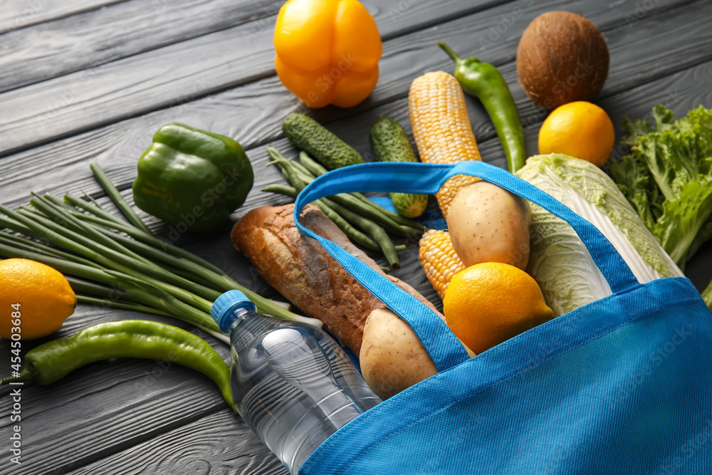 Eco bag with different products on wooden background