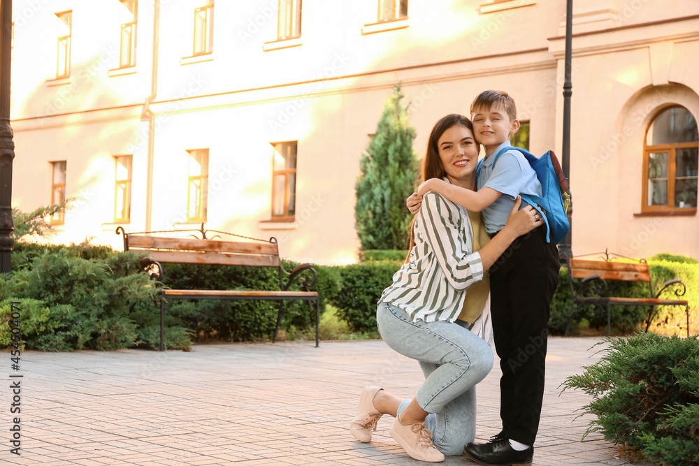 Mother saying goodbye to her little son near school