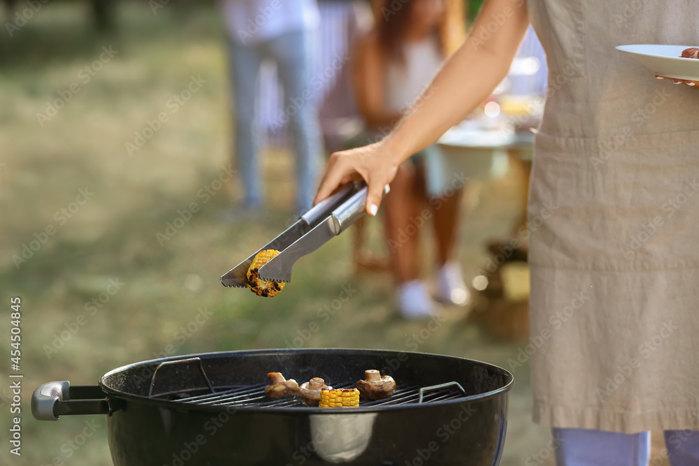 Young woman cooking food on barbecue grill outdoors