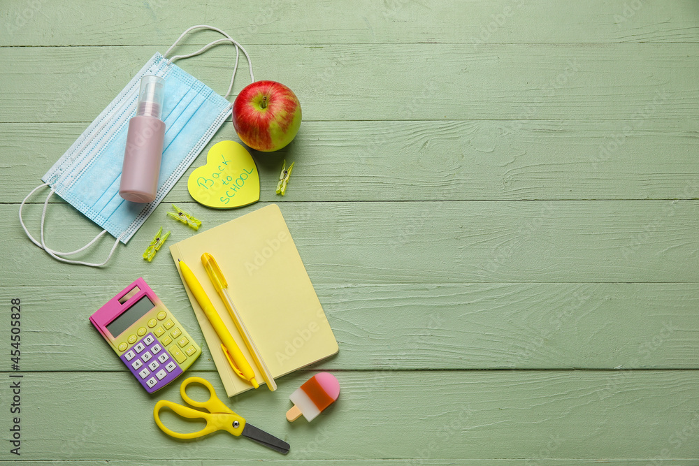 Paper with text BACK TO SCHOOL, stationery and medical masks on color wooden background