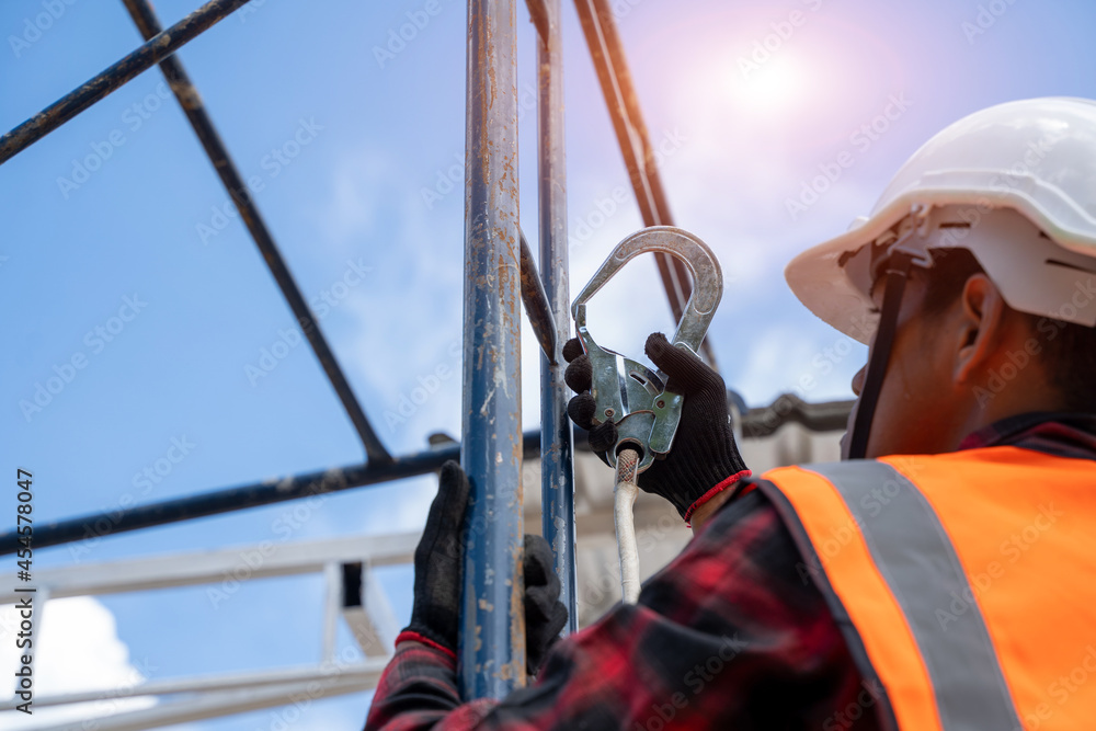 戴安全带的建筑工人在建筑工地高空作业，屋顶t