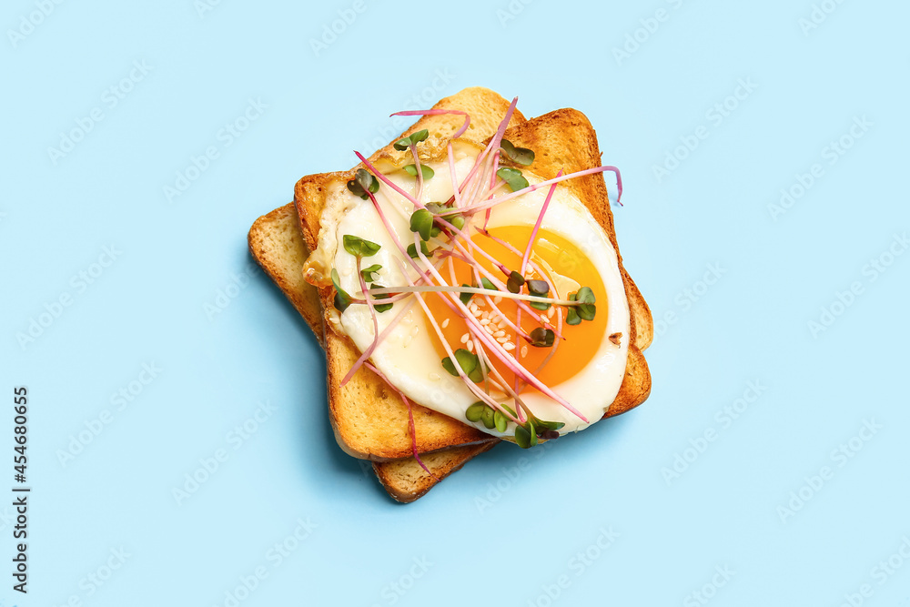 Tasty toasts with fried egg and micro green on color background