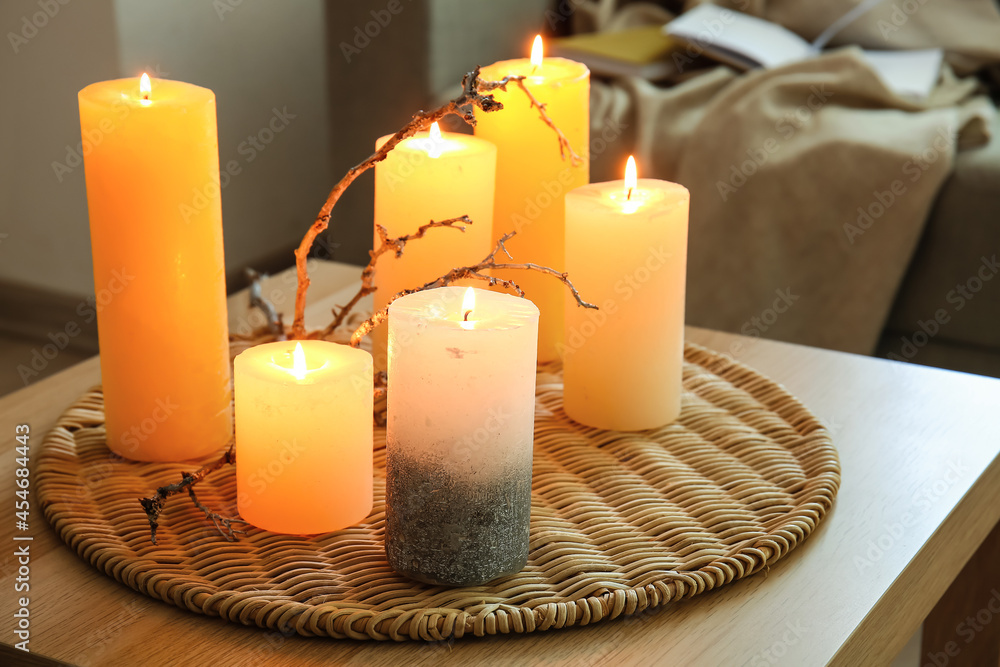 Burning candles on wooden table in living room, closeup