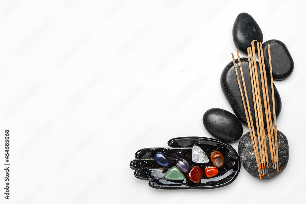 Composition with set of chakra stones and incense on white background