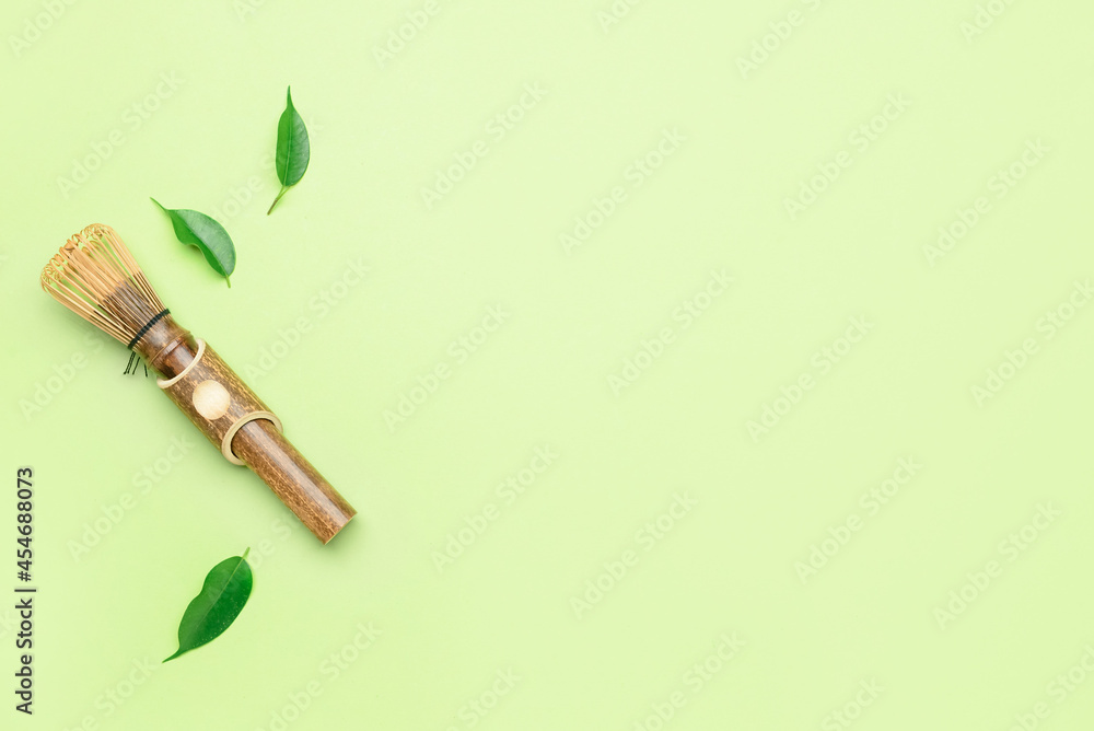 Composition with bamboo chasen and green leaves on color background