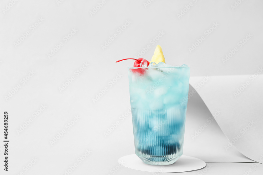 Glass of Blue Lagoon cocktail on light background