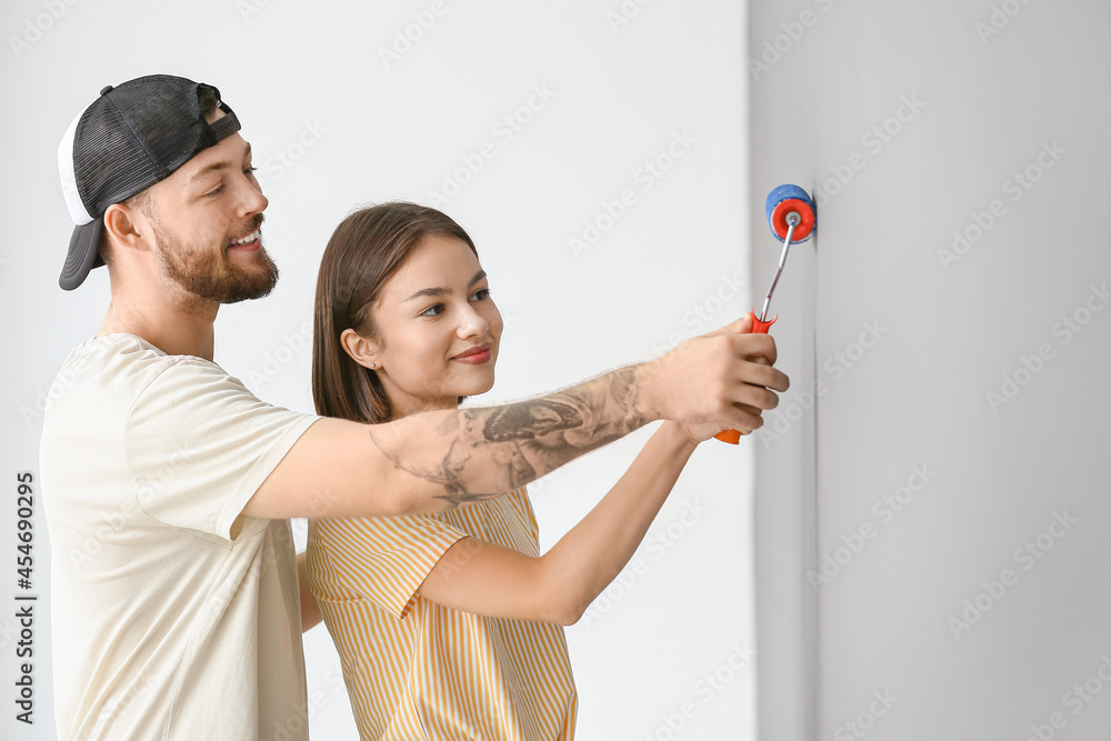 Young couple painting wall in room