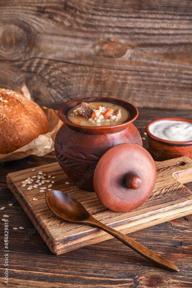 Cooking pot with tasty beef barley soup on table