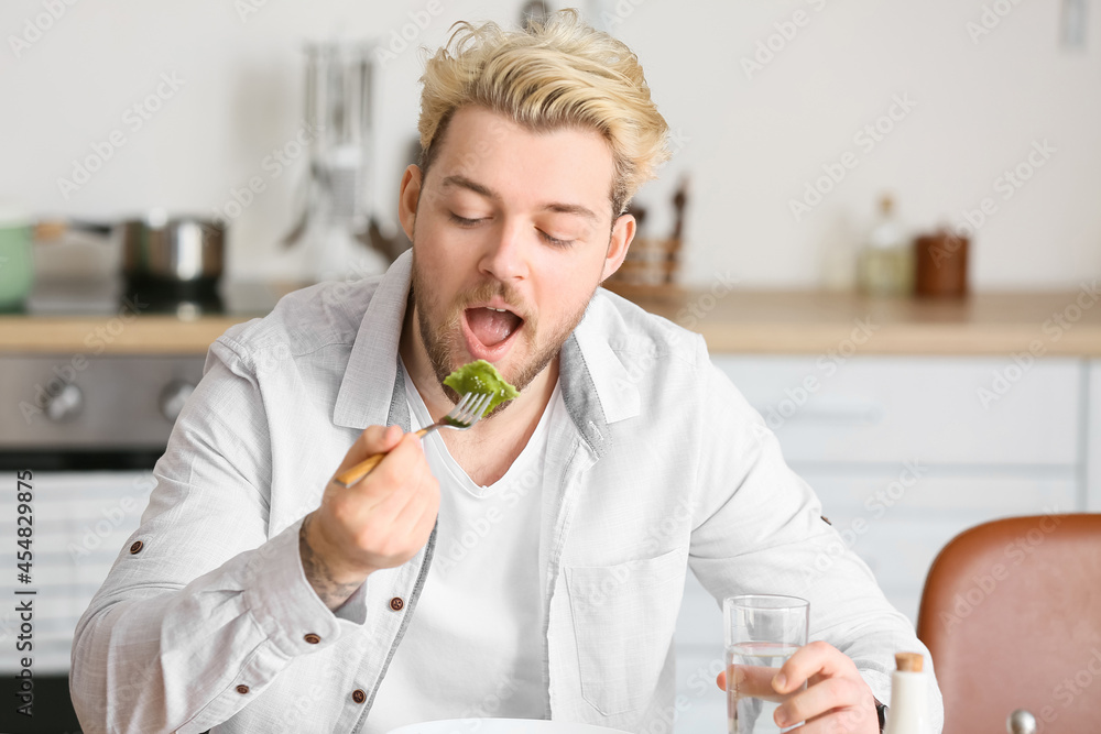 Young man eating tasty ravioli at home