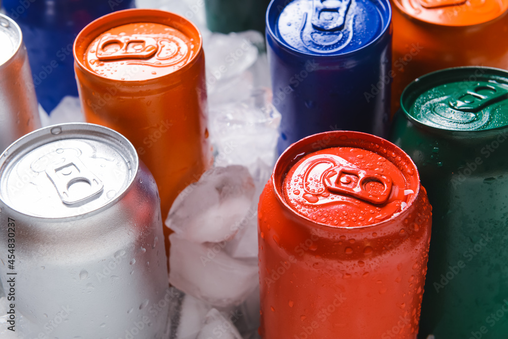 Cans of soda on ice cubes, closeup