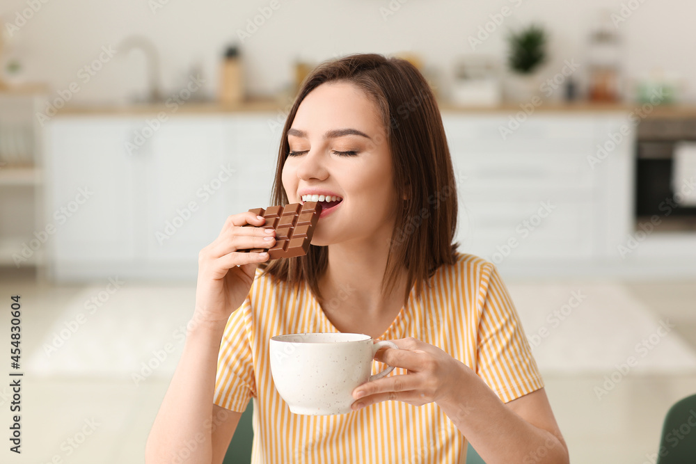 Beautiful young woman eating tasty chocolate at home