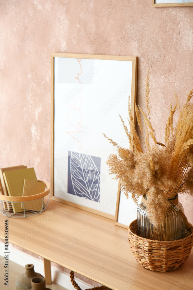 Stylish picture with vase and books on table near color wall