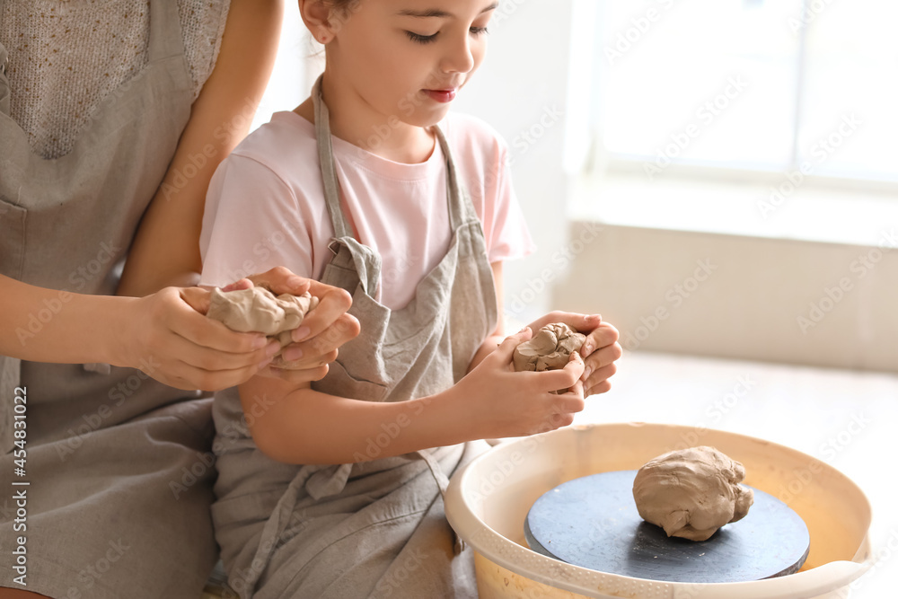 Little girl with her mother making ceramic pot at home