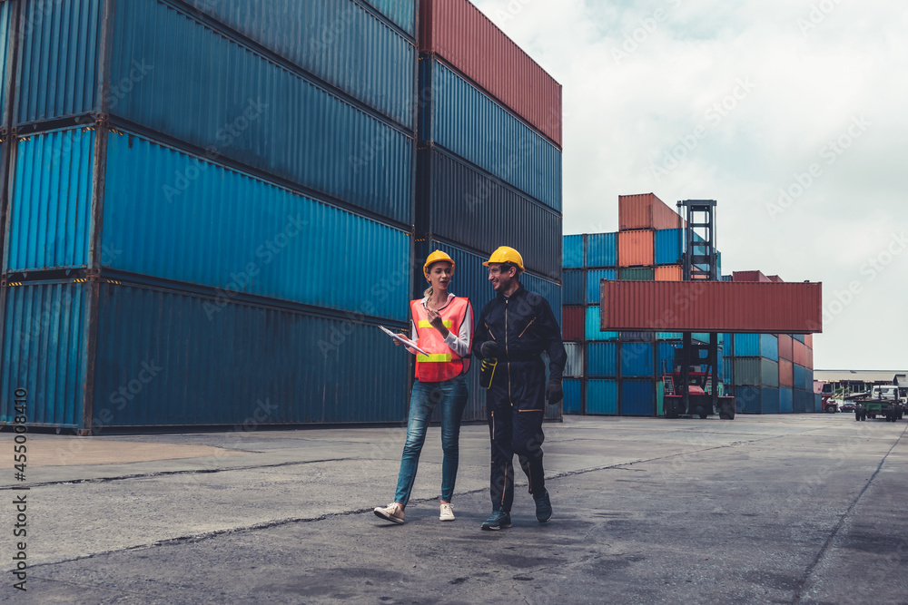 Industrial worker works with co-worker at overseas shipping container yard . Logistics supply chain 