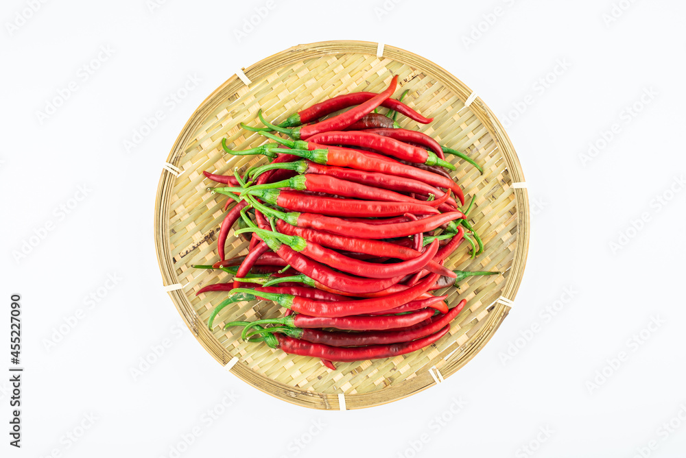 Bamboo sieve filled with fresh red peppers on white background