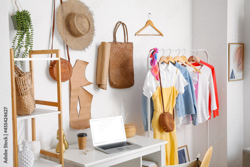 Interior of stylish room with modern workplace and clothes