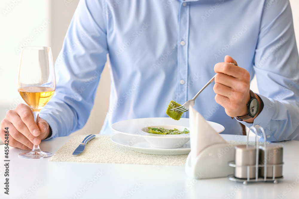 Young man eating tasty ravioli in cafe, closeup