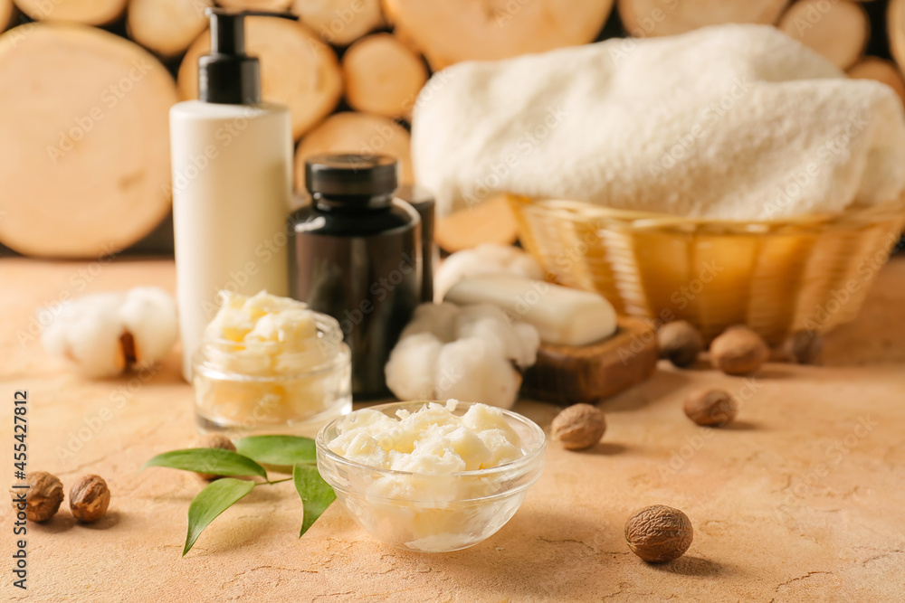 Bowl of shea butter and cosmetic products on table