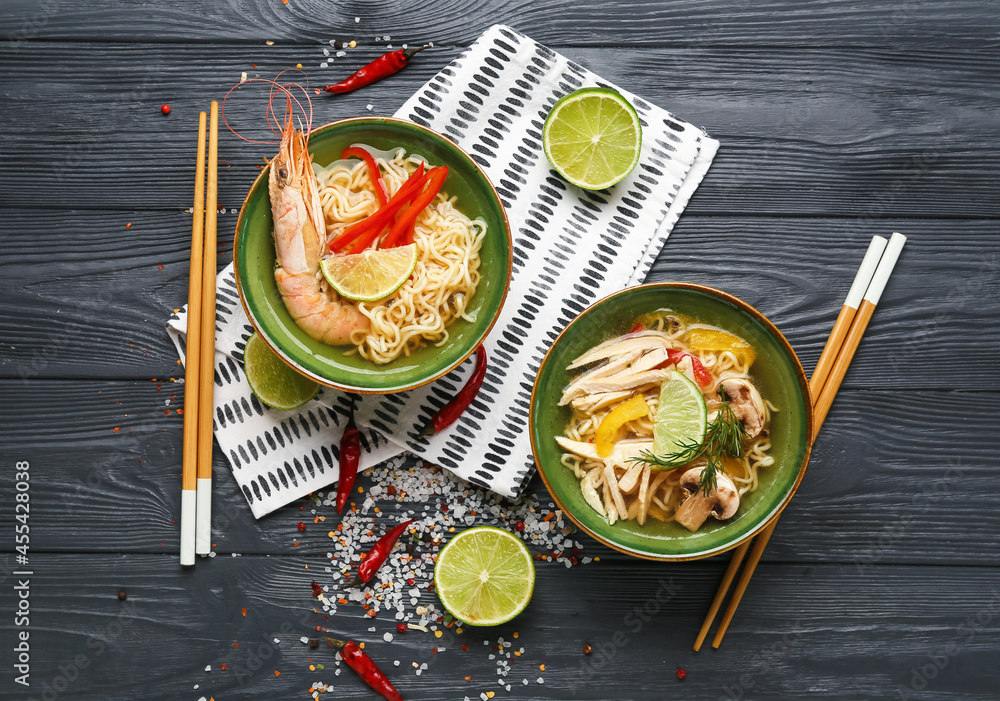 Bowls of tasty Thai soup with chicken and shrimps on dark wooden background